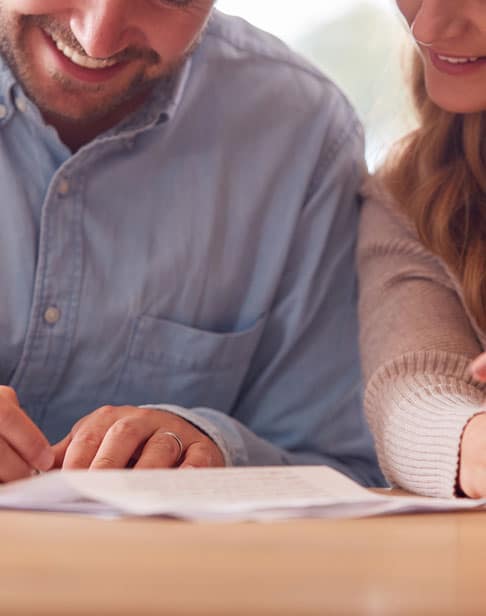 close-up-of-smiling-couple-signing-prenup-lawyers-pittsboro